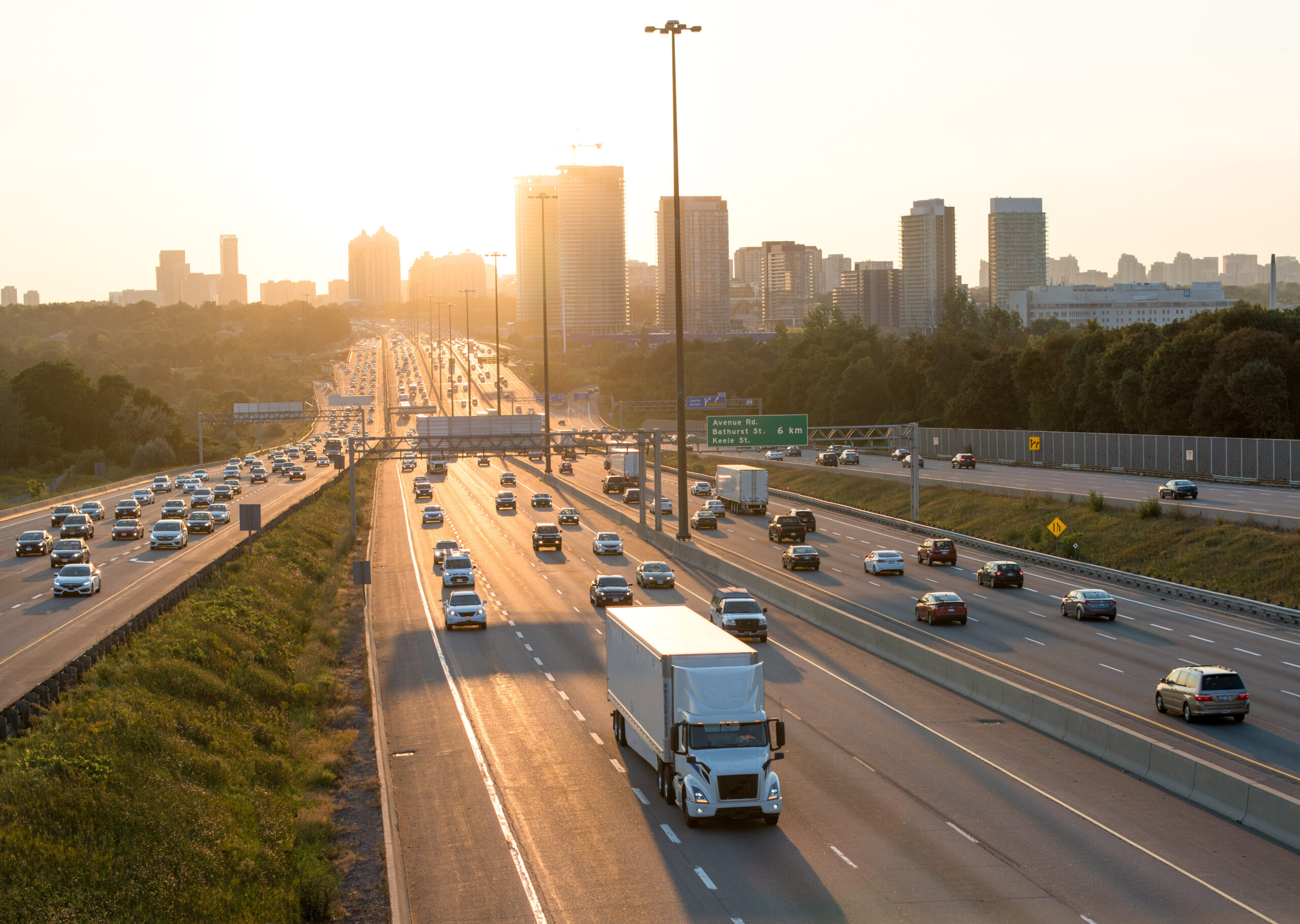Lane View of busy Highway 401 in Toronto Canada with reflection and high rise buildings during rush hours at the sunset