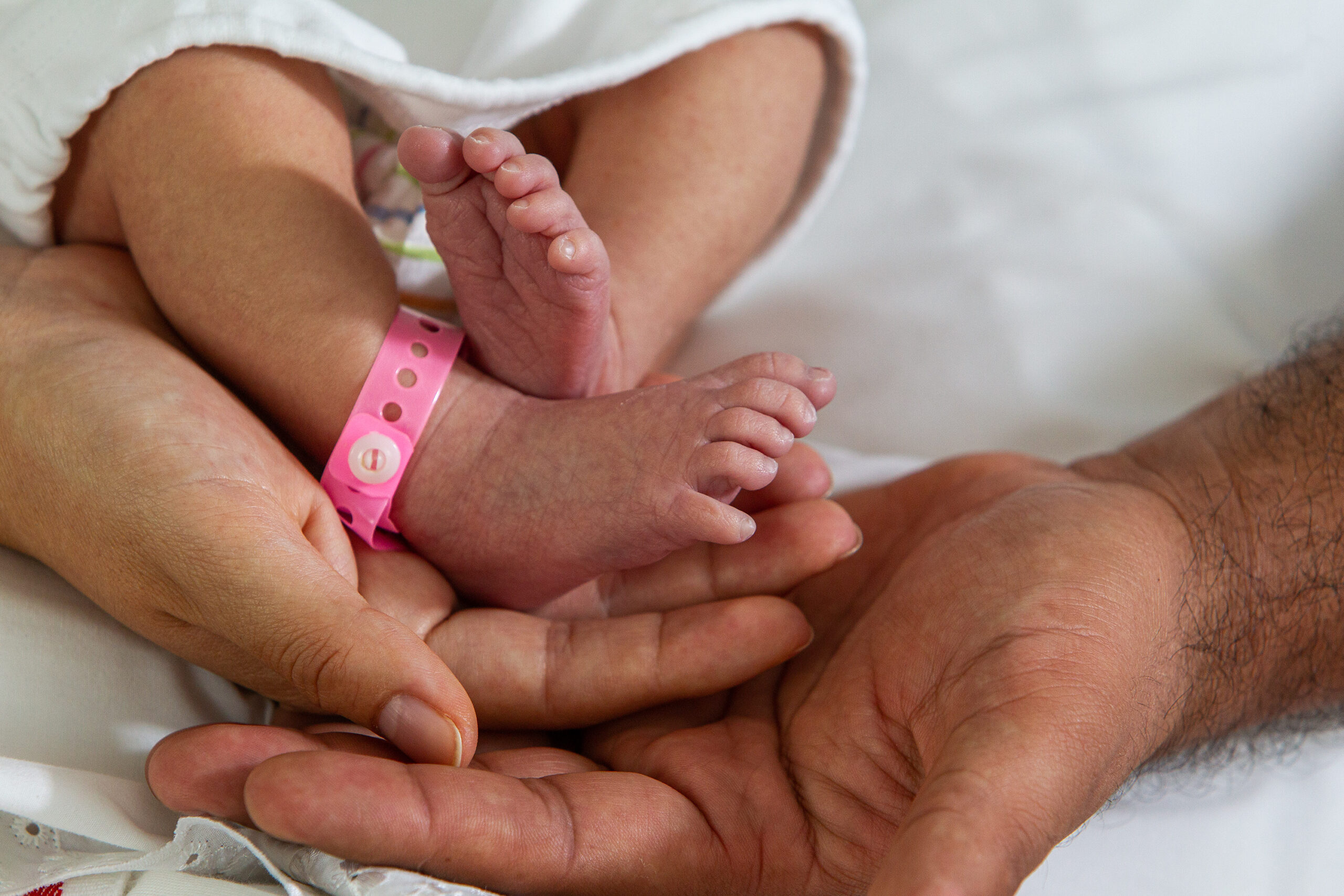 New born baby feet on the hands of a happy dad