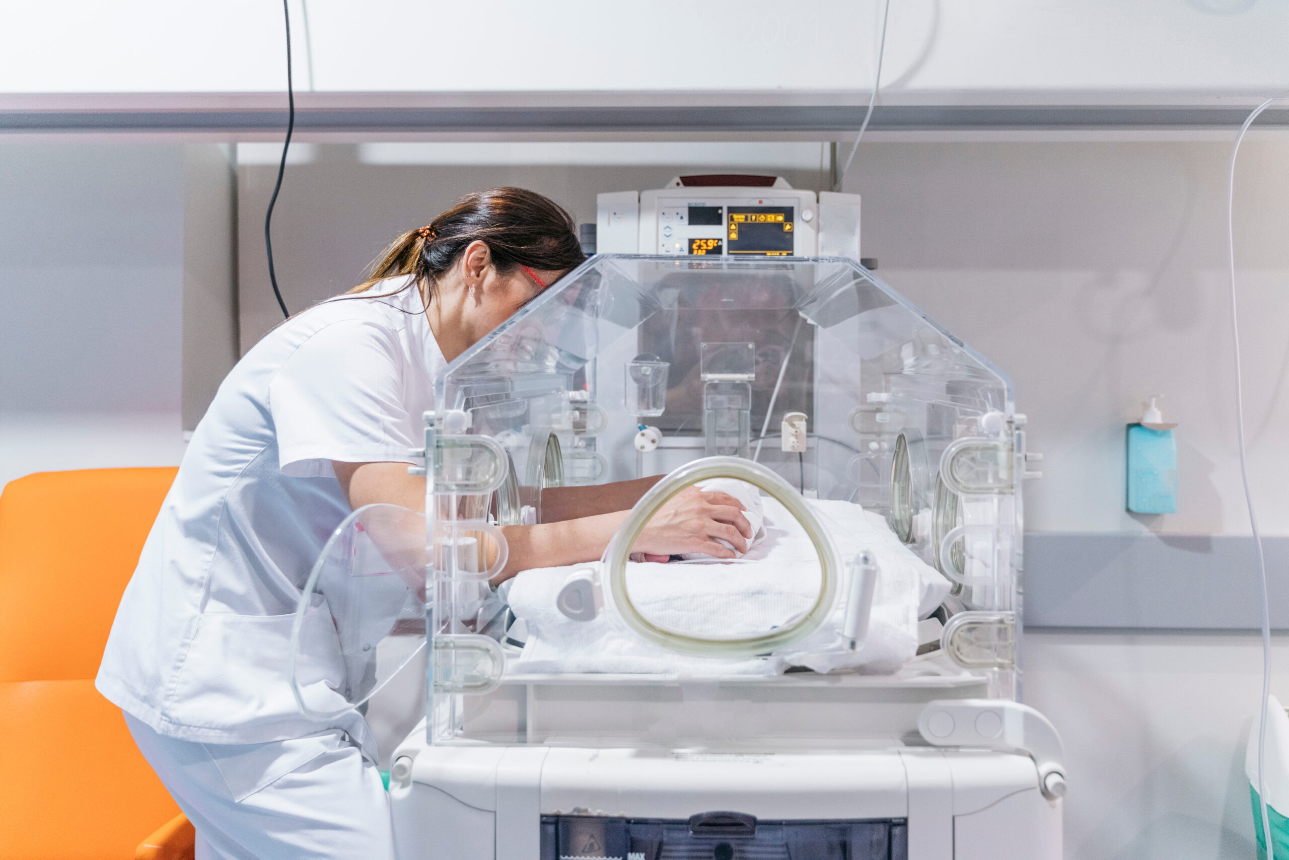 Female doctor examining newborn baby in incubator.a Night shift