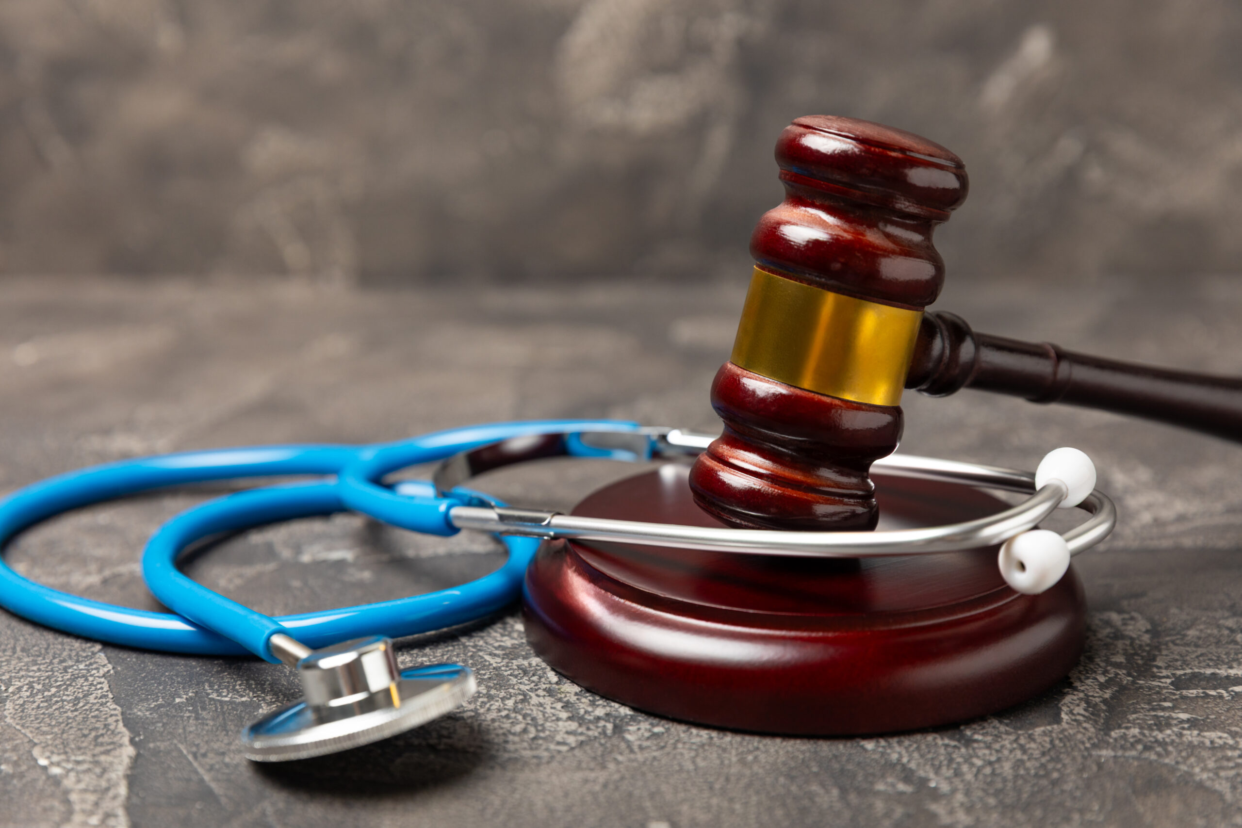 A stethoscope and hammer on a desk. Medical malpractice, personal injury lawyer, and healthcare legal aspects concept.Lawyer.Legal definition of medical negligence. Law concept.Healthcare and Medicine